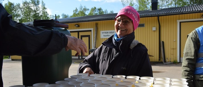 Iloinen nainen, Porin Ladun vapaaehtoinen, mehutarjoilupisteellä.