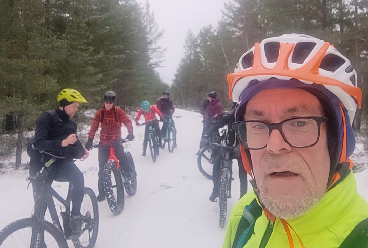 Talvikuva maastopyorailijoista, etualalla lenkkien vetaja, mieshenkilo kypara paassa