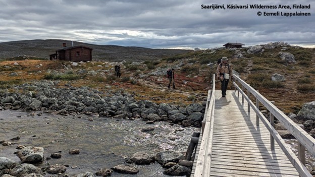 Silta oikeassa laidassa, ihminen kulkemassa. Maasto kivikkoinen.