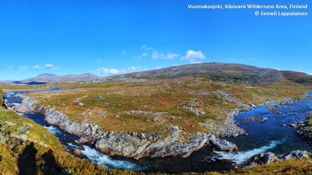Yläkulmasta kuvattu joki etualalla, loivaa tunturimaisemaa.